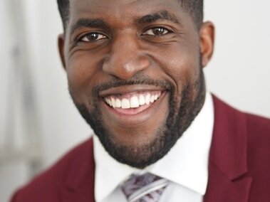 Portrait of Emmanual Acho, man smiling while wearing suit